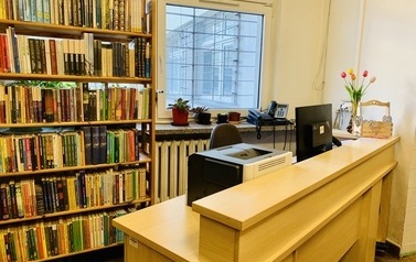 Lada biblioteczna usytuowana przy oknie, obok niej regał z książkami