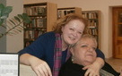 Dwie kobiety siedzą przed biurkiem, przytulają się.