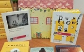 Na stole książki z domkiem z papieru.