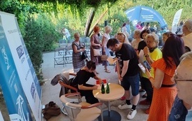 Kobieta podpisująca książki, wok&oacute;ł zebrana publiczność.