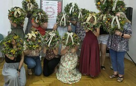 Zdjęcie grupowe kobiet z twarzami zasłoniętymi przez wieńce. 