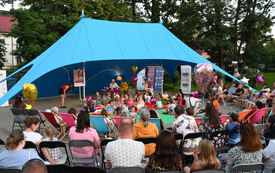 Namiot na placu i widownia zebrana na spotkaniu.