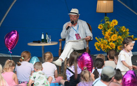 Aktor w kapeluszu czytający dzieciom.