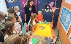 Kobieta tworzy ilustracje cyfrowe z papierowych rysunków podczas warsztatów z dziećmi.