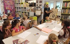 Ilustrator tworzy rysunki z dziećmi podczas warsztat&oacute;w. 
