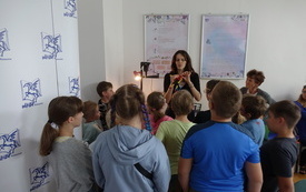 Kobieta pokazuje ludzika z papieru dzieciom.