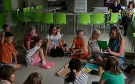 W grupie siedzą dzieci z ilustratorką.