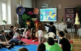 Pisarka siedzi z dziećmi i dyskutuje.