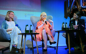 Trzy kobiety rozmawiające na scenie podczas panelu.