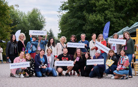 Grupa pracowników biblioteki i goście na zdjęciu grupowym.