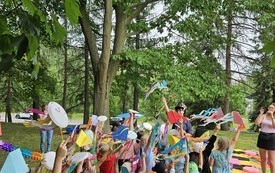 Dzieci w parku machają kolorowymi wstążkami.