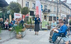 Dyrektorka biblioteki przemawia do zebranych na Narodowym czytaniu. W tle plakat i banery wydarzenia.