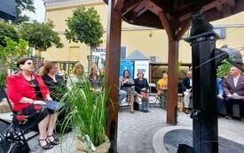 Goście, którzy czytali fragmenty poezji siedzący na krzesełkach wokół studni.