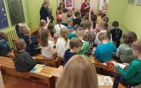 Grupa dzieci siedzi na spotkaniu z pisarką