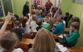 Grupa dzieci siedzi na spotkaniu w bibliotece
