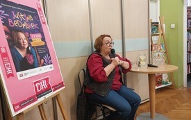 Pisarka z mikrofonem siedzi przed grupą dzieci