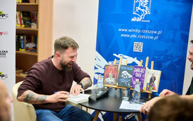 Śmiejący się mężczyzna podpisuje książkę