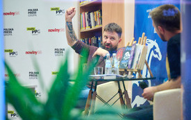 Mężczyzna z mikrofonem i uniesioną w g&oacute;rę ręką