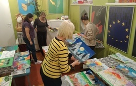 Cztery kobiety stoją w sali pełnej prac plastycznych