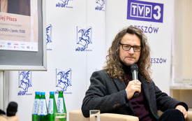 Mężczyzna z długimi kręconymi włosami z mikrofonem 