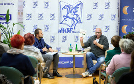 Pisarz i moderator spotkania, na fotelach podczas rozmowy.