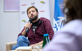 Ujęcie młodego pisarza przemawiającego do mikrofonu. 