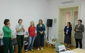 Cztery kobiety z naszyjnikami z lampek. Obok dwie kobiety w marynarkach.