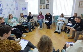 Wok&oacute;ł sali na krzesełkach siedzą uczestnicy warsztat&oacute;w.