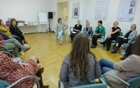 Uczestnicy spotkania siedzący wok&oacute;ł na krzesłach.