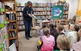 Dzieci słuchają pisarki, kt&oacute;ra opowiada im o książkach. 