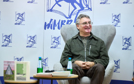 Uśmiechnięty autor siedzi w fotelu