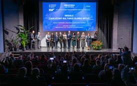 Grupa nagrodzonych bibliotekarzy pozuje do wsp&oacute;lnego zdjęcia stojąc na scenie