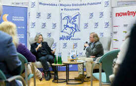 Dw&oacute;ch mężczyzn siedzących w fotelu i rozmawiających.