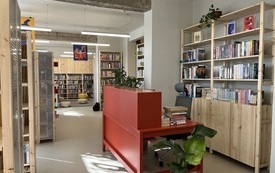 Czerwona lada biblioteczna, wok&oacute;ł regały z książkami.