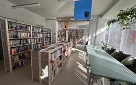 Regały z książkami i zielony st&oacute;ł 