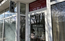 Przeszklone drzwi na kt&oacute;rych widnieją godziny otwarcia. Powyżej neon z literką B