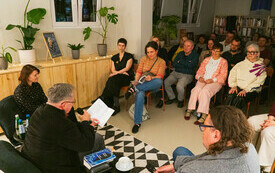 Widok sali bibliotecznej pełnej czytelnik&oacute;w na spotkaniu autorskim