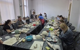 Uczestnicy warsztat&oacute;w siedzą przy stole warsztatowym
