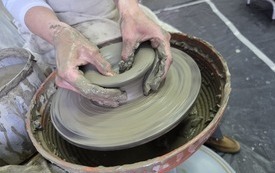 Koło garncarskie i ręce kształtujące naczynie gliniane
