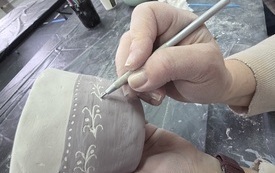 Kobiece ręce dekorujące gliniany kubek