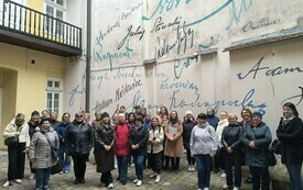 Grupa bibliotekarek przy ścianie kamienicy z autografami poet&oacute;w. 