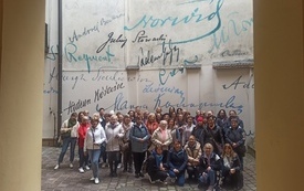 Fotografia grupowa pod ścianą kamienicy z autografami pisarzy. 