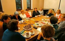 Przy stole siedzi grupa ludzi, którzy rozmawiają ze sobą.