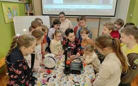 Grupa dzieci zgromadzona wok&oacute;ł stołu