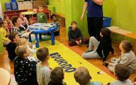 Grupa dzieci na dywanie bawi się klockami Lego