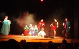 Na teatralnej scenie aktorzy w przebraniach.