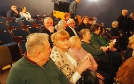 Grupa ludzi siedzi na widowni, rozmawiają ze sobą.