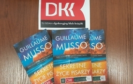 Na stole leżą trzy takie same książki i naklejka z logo DKK.