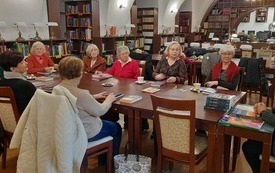 Kilka kobiet siedzi przy stole i rozmawia. 