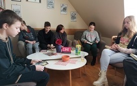 Wokół okrągłego stołu siedzą wszyscy zebrani na spotkaniu